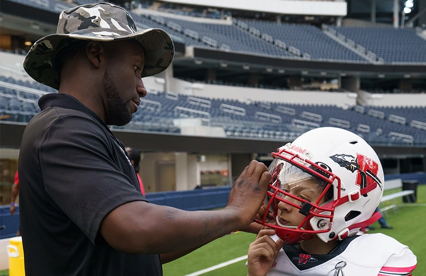 Youth tackle coach helping player